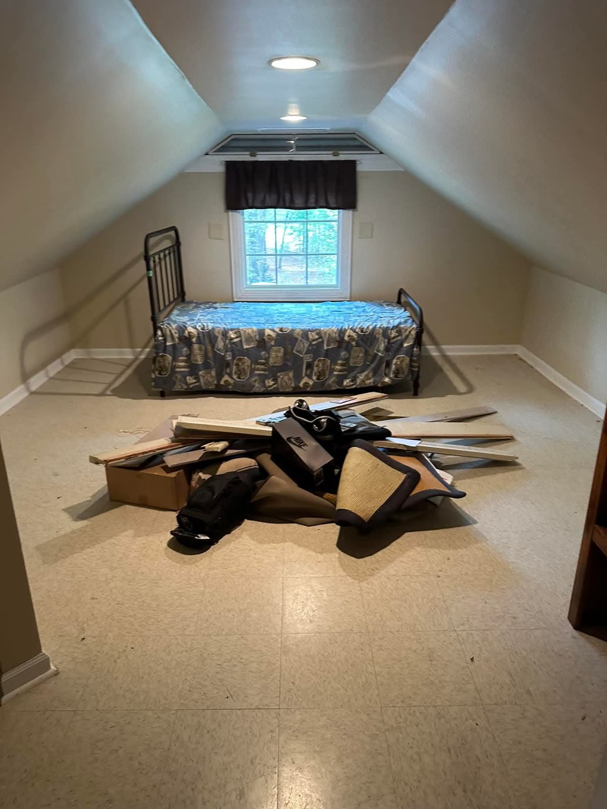 Attic room during a cleanout, with old boards, boxes and junk piled up for removal